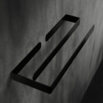 Nowoczesny, minimalistyczny wieszak łazienkowy w czarnym matowym wykończeniu, zamontowany na ciemnoszarej betonowej ścianie. Konstrukcja składa się z dwóch równoległych ramion o prostym, eleganckim designie, idealnych do zawieszania ręczników lub innych akcesoriów łazienkowych.