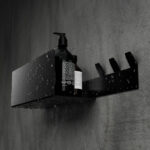 Nowoczesna, czarna półka łazienkowa z haczykami, wykonana z trwałego aluminium. Konstrukcja odporna na wodę, z widocznymi kroplami na powierzchni. Na półce umieszczone są eleganckie butelki z kosmetykami. Styl loftowy, minimalistyczny design pasujący do industrialnych wnętrz.