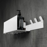 Nowoczesna, czarna półka łazienkowa z haczykami, wykonana z trwałego aluminium. Konstrukcja odporna na wodę, z widocznymi kroplami na powierzchni. Na półce umieszczone są eleganckie butelki z kosmetykami. Styl loftowy, minimalistyczny design pasujący do industrialnych wnętrz.