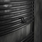 Podwójny haczyk na kaloryfer, aluminiowy, na tle eleganckiej łazienki oraz kaloryfera drabinkowego. W kolorze czarny mat