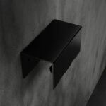 Czarny, minimalistyczny wieszak na ręczniki HUKI wykonany z malowanej proszkowo stali, montowany do ściany – widok z boku na prostokątną formę z zaokrąglonymi krawędziami i otworami montażowymi.