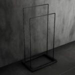 Stojak łazienkowy wolnostojący w kolorze matowej czerni, o prostym, geometrycznym kształcie. Minimalistyczna konstrukcja z dwiema poprzeczkami idealna do suszenia ręczników.
