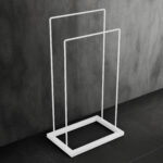Stojak łazienkowy wolnostojący w kolorze matowej bieli, o prostym, geometrycznym kształcie. Minimalistyczna konstrukcja z dwiema poprzeczkami idealna do suszenia ręczników.