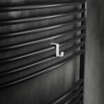 Pojedynczy haczyk na kaloryfer w kolorze biały mat, na tle eleganckiej ciemnej łazienki, oraz kaloryfera