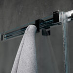 Dwustronny haczyk na kabinę prysznicową w kolorze czarnym zawieszony na kabinie wykonanej z szkła w tle nowoczesnej elegancje łazienki