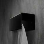 Czarny, minimalistyczny wieszak na ręczniki HUKI wykonany z malowanej proszkowo stali, montowany do ściany – widok z boku na prostokątną formę z zaokrąglonymi krawędziami i otworami montażowymi.