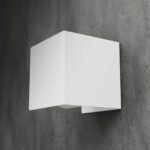 biały, metalowy uchwyt na papier toaletowy Nira, zamontowany na betonowej ścianie w nowoczesnej łazience – minimalistyczny design w stylu industrialnym