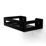 Czarna metalowa półka łazienkowa NAOS z matowym wykończeniem, zamontowana na ścianie, z perforowanym dnem i wysokimi bokami; na półce ustawione butelki kosmetyków.