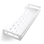 Biała metalowa półka łazienkowa NAOS z matowym wykończeniem, zamontowana na ścianie, z perforowanym dnem i wysokimi bokami; na półce ustawione butelki kosmetyków.