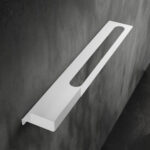 Nowoczesna biała półka łazienkowa Orion z wbudowanym uchwytem na ręcznik. Wykonana z metalu, o minimalistycznej, geometrycznej formie.